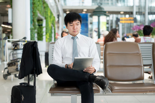 Asian businessman using digital tablet while waiting in lounge 