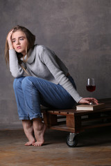 Tired girl posing with glass of wine. Gray background