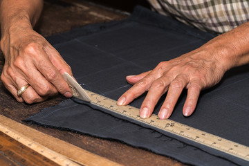 Tailor at work, drawing line on fabric with chalk

