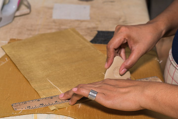 Tailor at work, drawing line on fabric with chalk
