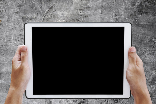 Hand holding digital tablet, with copy space on screen, on concrete texture background