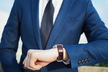 Businessman in elegant blue suit looking at luxury watch waiting