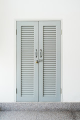 Closed and locked grey wood door , locked window in white wall b