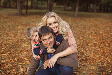 Fototapeta na wymiar Portrait happy parents with his their son in a park in the autumn