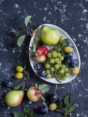 Fototapeta na wymiar Fresh fruit - grapes, pears, apples, plums on a dark background, top view