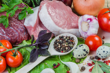 Raw meat, spices and vegetables on rustic wooden board