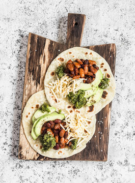 Spicy Beans, Avocado And Green Chile Sauce Tortilla On A Rustic Cutting Board On A Light Background. Top View