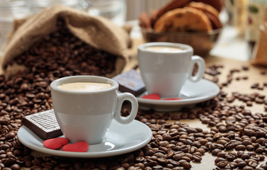 Coffee beans out of a sack and two cups of coffee