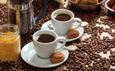 Coffee beans out of a sack and two cups of coffee