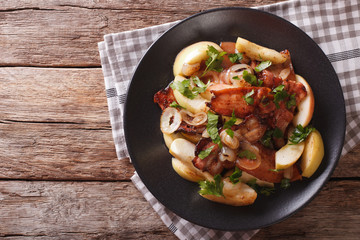 Swedish cuisine: Fried bacon with onion and stewed green apples close up. horizontal top view
