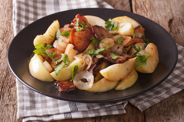 Tasty Fried bacon with onion and stewed apples close up on a plate. horizontal
