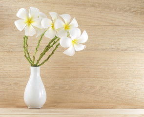 white plumeria or frangipani bouquet in simple pottery vase on desk floor