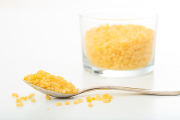 Yellow sugar in a spoon and a glass bowl