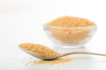Yellow sugar in a spoon and a glass bowl
