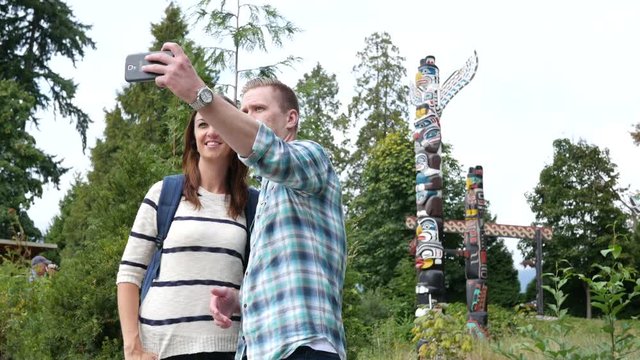 Couple taking a selfie in front of totem pole