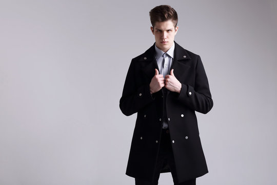 Fashion shot of a young handsome man in black coat.