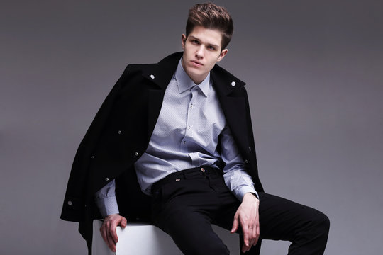 Fashion shot of a young handsome man in black coat.