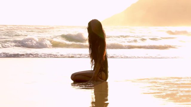 Beautiful woman lying on the sand reflected in it. Laughter and spray water. In slow motion. 4K