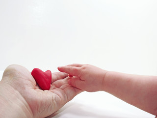 Man's and child hands with red heart