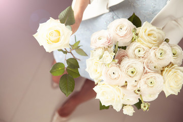 Woman holding bouquet of ranunculus and roses.