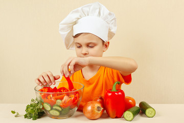 Young chef puts chopped vegetables for a salad in a bowl