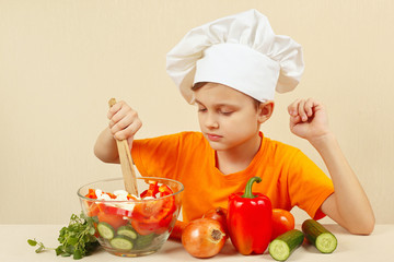 Young chef mixing the vegetables in a bowl with salad