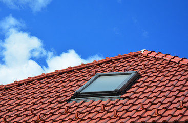 Naklejka premium Skylight on red ceramic tiles house roof. Skylights, Roof Windows and Sun Tunnels.