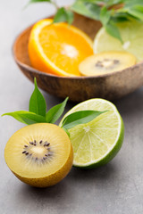 Fototapeta na wymiar Mixed citrus fruit lemons, orange, kiwi, limes on a gray backgro