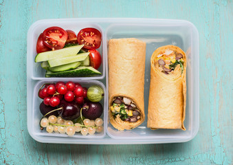 Healthy lunch box with tortilla wraps , fruits and vegetables, top view