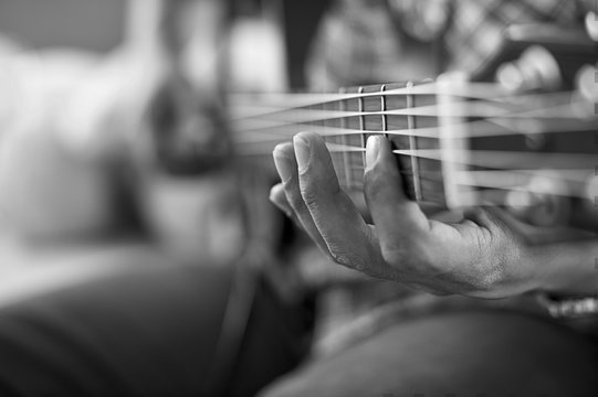 playing acoustic guitar, barre chord,selective focus,black and w