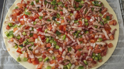 Raw pizza with vegetables and bacon close up before putting it on the oven