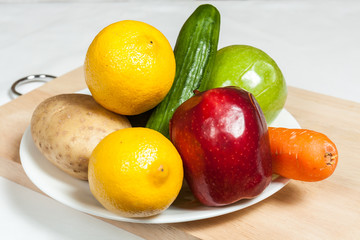 Plate of fruits and vegetables on chopping board