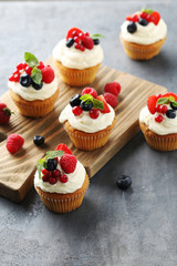 Tasty cupcakes with berries on cutting board