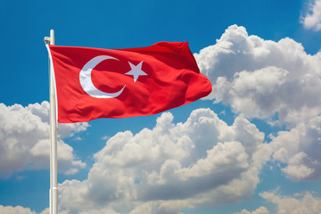 turkish flag waving in front of cloudy blue sky