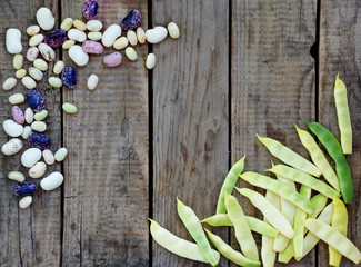 Young beans and asparagus different varieties and colors on a wooden background.