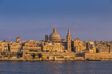 Fototapeta na wymiar Valletta, Malta - The beautiful St.Paul's Cathedral and the ancient city of Valletta at sunset with clear blue sky
