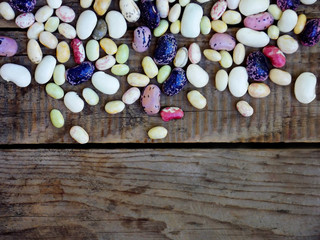 young beans of different varieties and colors above border on wooden background. selective focus