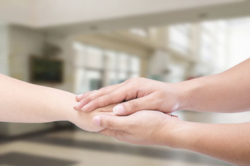 Hand of medical doctor carefully holding patient's hands.
