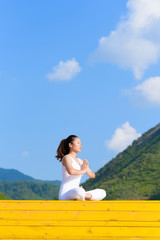 Young woman does yoga exercise outdoors.