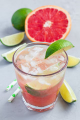 Cold pink cocktail with fresh grapefruit, lime and ice, vertical