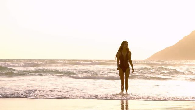 Woman walking away from sea in slow motion.