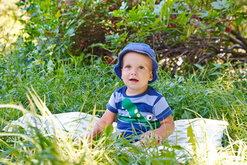 Little boy in panama sitting on the grass