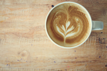 Coffee in white cup on wood table in coffee shop.