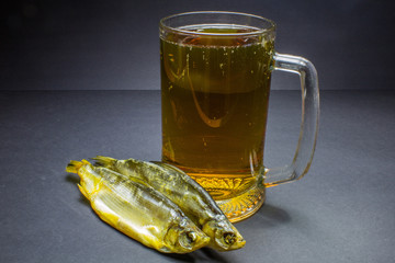 Beer and dried fish snack on black background.