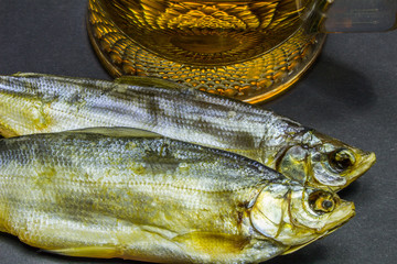 Beer and dried fish snack on black background.