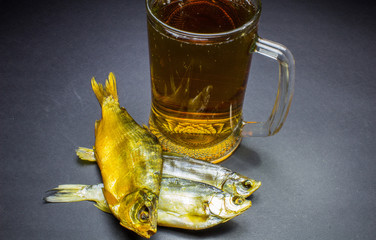 Beer and dried fish snack on black background.