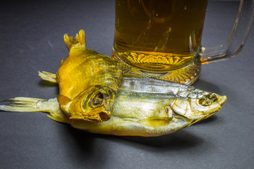 Beer and dried fish snack on black background.