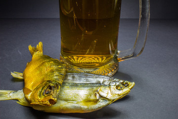 Beer and dried fish snack on black background.