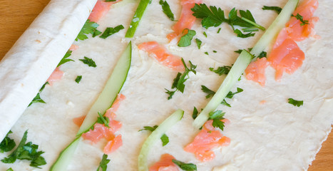 Half finished poll with salt salmon, cucumber, parsley on a wooden board under a daylight - 119264803