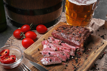 Tasty grilled steak with beer on cutting board